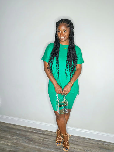 Woman wearing a kelly green 2 piece set standing against a white wall.