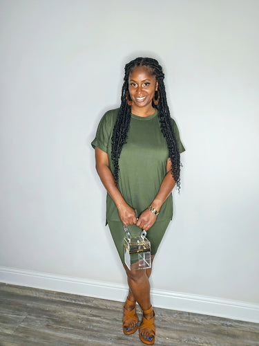 Woman wearing a dark olive 2 piece set standing against a white wall.