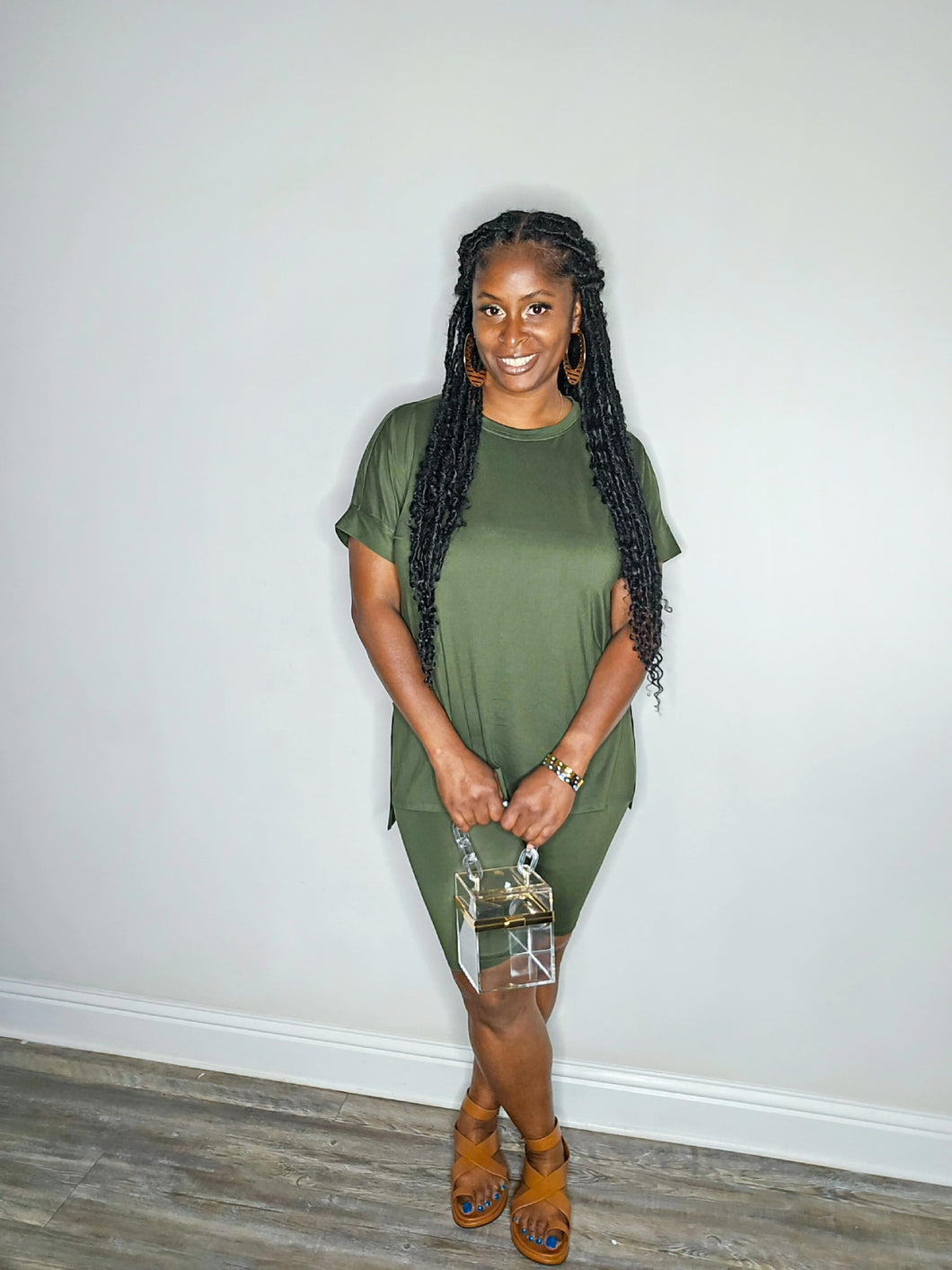 Woman wearing a dark olive 2 piece set standing against a white wall.