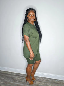Woman wearing a dark olive 2 piece set standing against a white wall.