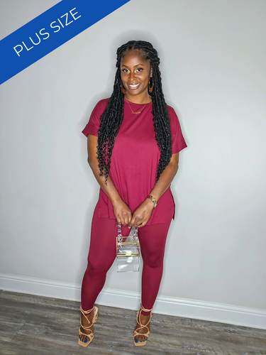 Woman wearing a cabernet plus-size outfit against a plain wall.